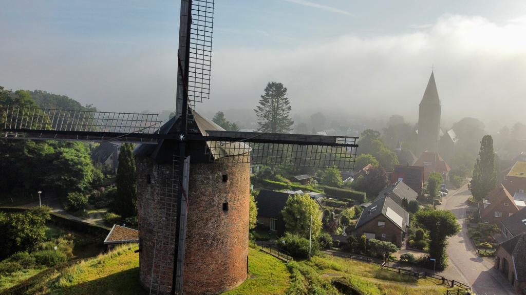 Torenmolen van Zeddam in de ochtendmist met de kerk op de achtergrond